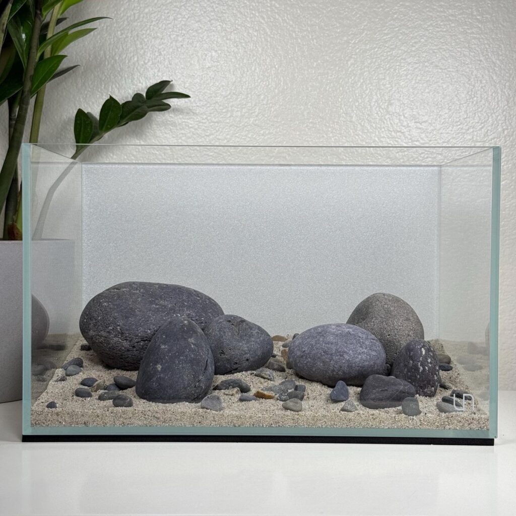 Rocks for Fish Tank: A Complete Guide to Safe, Stylish Aquascaping
Introduction: Why Rocks Matter in Your Fish Tank Setup
Rocks are more than just decorative elements—they play a crucial role in building a healthy, engaging, and stable environment inside your aquarium. Whether you're aiming for a natural aquascape or just want to give your fish places to hide and explore, choosing the right rocks for fish tank setups can make all the difference.

But here’s the twist: not all rocks are created equal. Some may look great but can disrupt water chemistry, harm fish, or leach toxins. That’s why it’s important to make informed choices.

In this detailed guide, we’ll cover everything you need to know—from types of rocks, safety checks, placement techniques, to design inspiration. If you're looking to enhance your aquarium both visually and functionally, this is where you start.

Why Use Rocks in a Fish Tank?
Adding rocks to your aquarium does far more than beautify your tank.

1. Natural Aesthetics
Rocks bring depth and realism to your setup. Whether you're replicating a riverbed or a rocky cliff, the right rock selection creates a more immersive environment.

2. Shelter and Territory
Many fish species feel secure with hiding spots. Rocks provide caves, crevices, and shaded areas, which can reduce stress and aggression—especially for territorial fish like cichlids.

3. Support for Aquatic Plants
Certain rocks serve as anchors for aquatic plants, mosses, and ferns. This makes them essential for aquascaping and plant-friendly environments.

4. Biological Benefits
Porous rocks can foster beneficial bacteria colonies, improving biological filtration and overall water quality.

What Makes a Rock Safe for Fish Tank Use?
Before dropping just any rock into your aquarium, it’s crucial to evaluate its safety.

H3: What to Watch Out For
Toxic Minerals: Some rocks contain metals or elements that can leach into the water.

pH Alteration: Rocks like limestone can increase pH and hardness, which may not be suitable for all fish.

Sharp Edges: Can injure delicate fins or bottom-dwelling species.

H3: Safety Tests You Can Do at Home
✅ Vinegar Test
Drop white vinegar on the rock. If it fizzes, the rock contains calcium carbonate and may alter water chemistry—avoid unless you're keeping hard water species.

✅ Scratch Test
Use a knife or coin to scratch the rock. If it easily flakes or crumbles, it might not be suitable for long-term submersion.

✅ Boiling
Boil the rock in water for 15–20 minutes to kill bacteria, parasites, or algae before placing it in your tank. Note: Don’t boil rocks that hold air pockets (like lava rocks), as they can explode.

Types of Rocks for Fish Tank: Safe and Popular Choices
H2: 1. Seiryu Stone
Grey-blue color with white veins

Slightly raises pH

Popular in aquascaping (especially Iwagumi layouts)

Best for planted freshwater tanks

H2: 2. Dragon Stone (Ohko Rock)
Earthy, brown tones with a textured surface

Lightweight and easy to stack

Neutral effect on water chemistry

Great for creating caves and cliffs

H2: 3. Lava Rock
Extremely porous—excellent for beneficial bacteria

Neutral to slightly alkaline

Works well in both freshwater and saltwater tanks

Supports moss and other epiphytes

H2: 4. Slate
Flat and stackable

Neutral in water chemistry

Commonly used for creating ledges or cave structures

H2: 5. Texas Holey Rock
White rock full of holes and crevices

Raises pH and hardness (ideal for African cichlids)

Not recommended for soft water species

H2: 6. Pagoda Rock
Layered stone with a unique, sharp-looking formation

Adds drama and verticality

Neutral in water chemistry

Rocks You Should Avoid
Not every rock is aquarium-safe. Some can alter water conditions drastically or harm your fish.

🚫 Avoid These:
Limestone – Raises pH and hardness

Marble – Same as limestone, bad for soft-water tanks

Sandstone – Can disintegrate over time

Geodes/Crystals – May contain heavy metals

Painted Rocks – Toxic coatings can peel and pollute water

If in doubt, always source rocks from aquarium-specific suppliers rather than landscaping or hobby stores.

How to Clean and Prepare Rocks for Your Aquarium
Even if you buy aquarium-safe rocks, they still need cleaning before going into your tank.

Step-by-Step Cleaning Guide:
Scrub with a Brush
Use a stiff-bristle brush to remove loose dirt, debris, or dust.

Soak in Warm Water
Let rocks soak in clean, dechlorinated water for a few hours.

Boil or Bake (Optional but Effective)
Boil for 15-20 minutes or bake at 200°F for 30 minutes to kill pathogens.
Warning: Avoid this with porous rocks that can crack or explode.

Rinse and Let Cool
Never add hot rocks to your tank—let them cool completely.

Aquascaping Ideas with Rocks for Fish Tank
Designing your tank layout with rocks can transform your aquarium from basic to breathtaking.

H3: Iwagumi Style (Minimalist Zen)
Uses a few large Seiryu stones

Symmetry, negative space, and balance are key

Perfect for planted tanks with small fish like tetras or rasboras

H3: Riverbed Theme
Mix of smooth river rocks and driftwood

Mimics natural streams and is ideal for species like loaches and corydoras

H3: Cichlid Caves
Stack holey rocks or slate to create layered cave systems

Helps reduce aggression and gives shelter to fry

H3: Lava Rock Jungle
Lava rock base covered in moss and Java ferns

Adds height and lush greenery to planted aquariums

Rock Placement Tips for Safety and Style
Secure Stacking: Use aquarium-safe epoxy if needed to prevent collapses

No Glass Contact: Place rocks on a foam mat or egg crate to avoid scratching or cracking the tank base

Leave Open Space: Fish need swimming room—don’t overcrowd

Consider Maintenance Access: Make sure rocks don’t block filter intakes or heaters

How Rocks Affect Water Chemistry
Depending on the type of rock, your tank’s pH and hardness can be affected—positively or negatively.

H3: Rocks That Raise pH
Texas Holey Rock

Limestone

Coral Rock (not technically a rock but used in cichlid tanks)

These are ideal for hard-water species like African cichlids.

H3: Neutral Rocks (Best for Most Tanks)
Slate

Lava Rock

Dragon Stone

Seiryu Stone (minimal effect)

Always monitor your water parameters weekly, especially after adding new décor.

Budget Breakdown: Cost of Rocks for Fish Tank
Rock Type	Average Price (per lb)	Best For
Seiryu Stone	$4–$6	Aquascaping, planted tanks
Dragon Stone	$3–$5	Natural-looking setups
Lava Rock	$1–$2	Filtration, plant anchoring
Slate	$1–$3	Ledges, caves
Holey Rock	$5–$8	Cichlid tanks

Tip: Many local fish stores sell rocks by weight—take only what you need to control cost.

Personal Experience: How Rocks Changed My Aquarium Game
When I first added rocks for fish tank setups, I didn’t expect much beyond aesthetics. But I was surprised at how much calmer my fish became. My bettas and bottom dwellers like cory cats started exploring, hiding, and even showing new behaviors I hadn’t seen before.

In one tank, I used lava rocks as a base and tied moss to them. It turned into a lush underwater garden, and my shrimp population exploded. The change was not just visual—it improved the health of the entire system.

Final Thoughts: Building a Natural Home for Your Fish
Rocks do more than just sit there—they shape the environment your fish call home. When thoughtfully selected and arranged, rocks for fish tank use can bring both style and function to your aquarium.

They provide shelter, enhance filtration, and create a world your fish can truly thrive in.

So whether you're designing a minimalist Iwagumi layout or a complex cichlid cave system, choose your rocks with care—and watch your underwater world come alive.

Want more aquarium inspiration?
Explore our guides on:

Best plants to pair with aquarium rocks

DIY rock backgrounds for tanks

How to maintain water quality in aquascaped setups

Start designing, and let your aquarium reflect the beauty of the wild.









Ask ChatGPT

Unlock more with Plus
ChatGPT Plus gives you higher limits, smarter models, and Sora for video.

Get Plus




Tools




